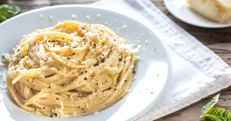 Cacio e pepe på en vit tallrik på ett matbord.