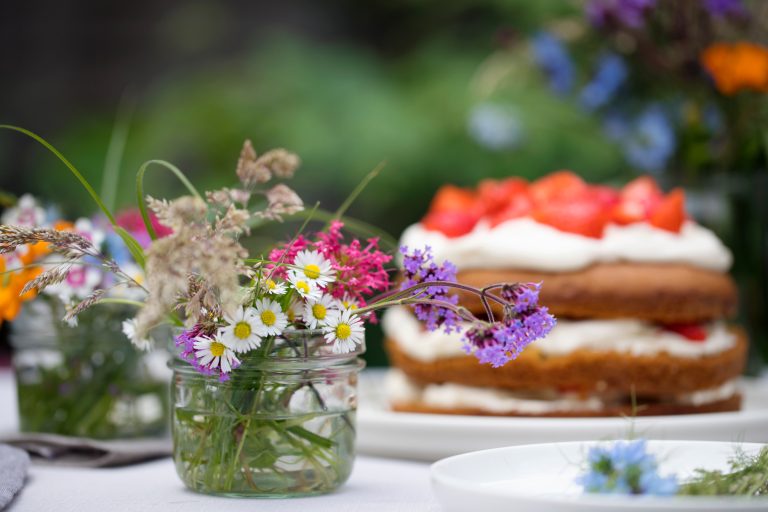 sommarens sommarbord med härlig jordgubbstårta och vackra blommor på ett bord